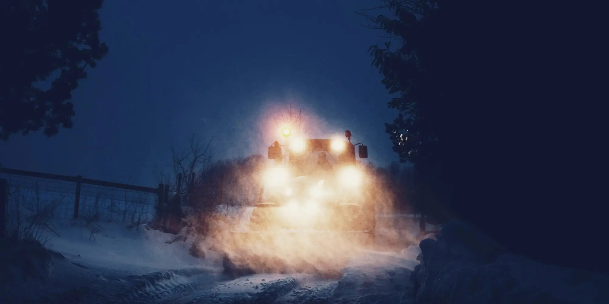Chasse-neige en intervention de nuit sur une route enneigée